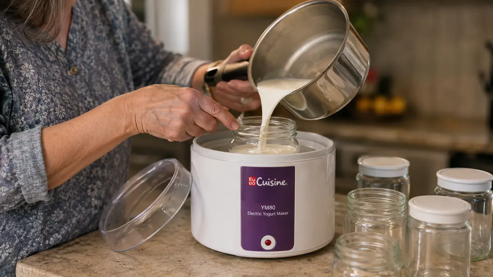 An older woman's hands pouring warm milk into a small glass jar set inside a white electric yogurt maker base